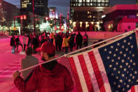 A Trump supporter demonstrating against the election results holds an American flag as counter protestors stand across the street outside the central counting board at the tcf Center in Detroit, Thursday, Nov. 5, 2020. (AP Photo/David Goldman)