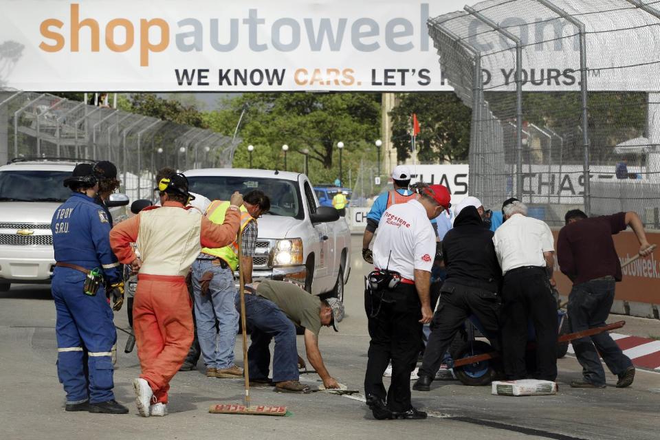 Work crews look over the asphalt patch on the road course during IndyCar's Detroit Grand Prix auto race on Belle Isle in Detroit, Sunday, June 3, 2012. The race was red flagged 63 minutes into the race because of the road condition. (AP Photo/Carlos Osorio)