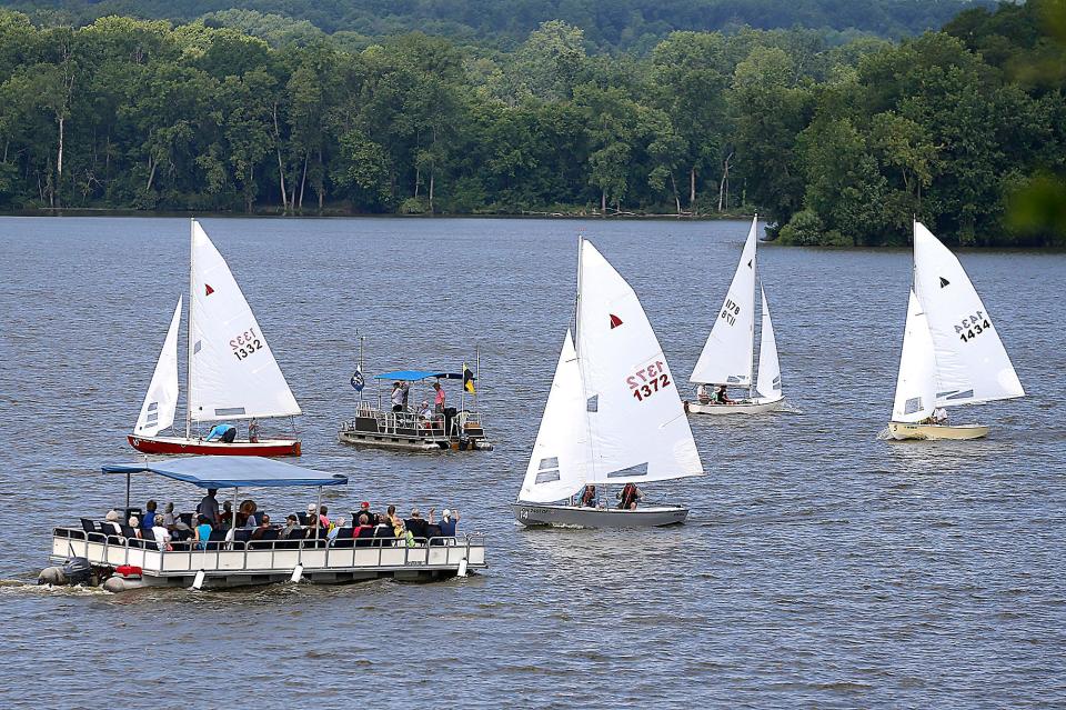 A spectator pontoon boat moves past the sailboats as they compete in the Interlake Sailing Class Association National Regatta at Charles Mill Lake on Thursday, July 21, 2022.