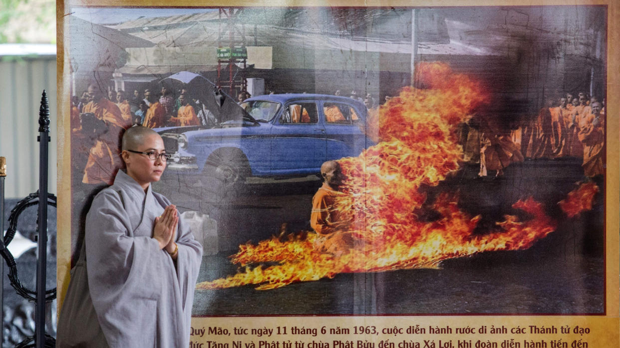  A Buddhist monk stands next to a banner with a picture of monk Thich Quang Duc, who set himself on fire on a busy Saigon street corner in 1963. 