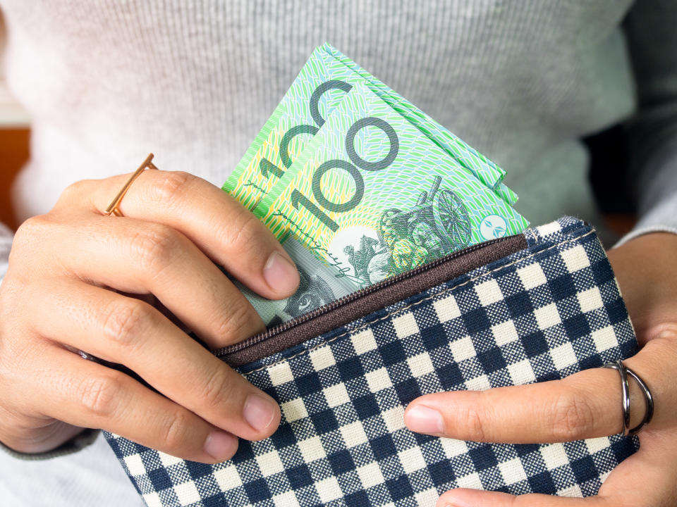 Woman pulling $100 notes from her wallet.