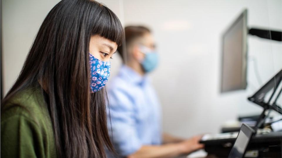 Una empleada usando mascarilla en una oficina