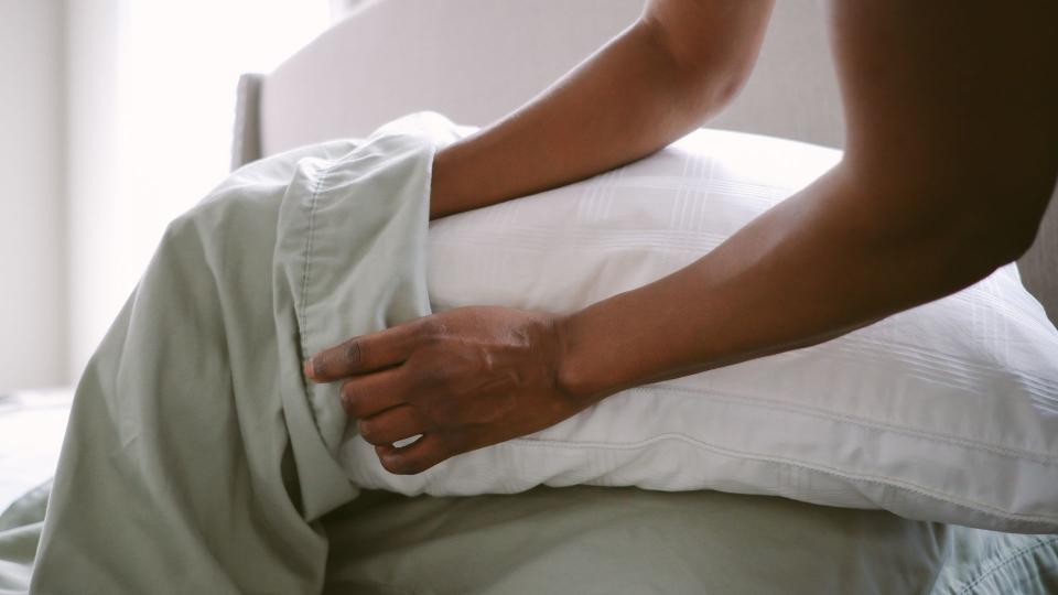 How Many Pillows Should You Sleep With - News piece - A woman puts a pillowcase on the pillows