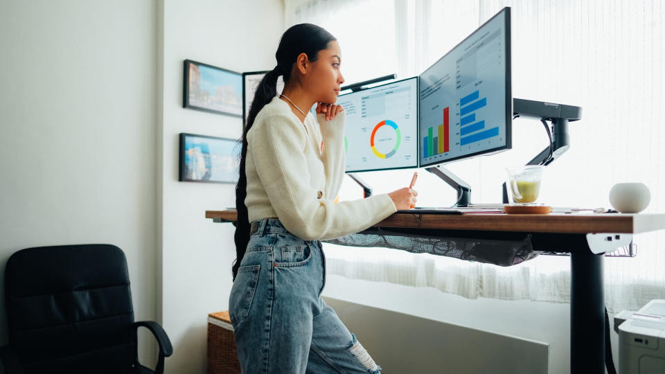 A woman standing at a desk with large computer screens on it