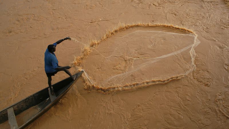 A fisherman casts his net near a dam in the rain-swollen Niger River in Niamey, Niger, on Friday, July 31, 2009. A boat capsized in the Niger River after a wedding killing over 103 people.