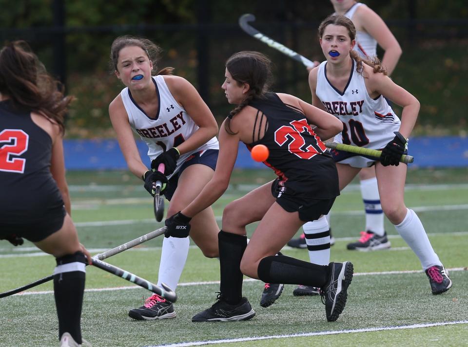 From left, Horace Greeley's Nina Byrne (14) gets a pass off in front of Mamaroneck's Kate Orchanian (27) during field hockey action at Horace Greeley High School in Chappaqua Oct. 12, 2022. Greeley won the game 1-0.