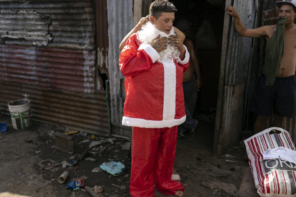 Tito Perez gets helps with his Santa Claus costume as he readies for a pre-Christmas celebration organized by "Los Chicos de la Via" soup kitchen, in Buenos Aires, Argentina, Saturday, Dec. 23, 2023. (AP Photo/Rodrigo Abd)