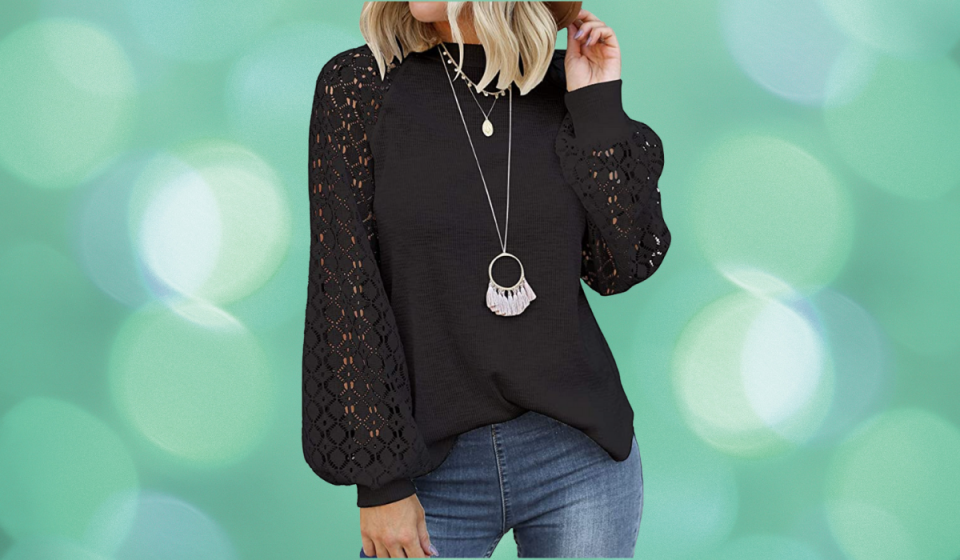 The torso of a woman is shown wearing a black version of the lace-sleeve blouse along with blue jeans and silver necklaces.