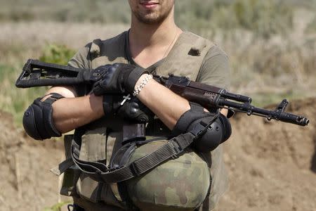 A Ukrainian serviceman holds his weapon as he guards a military camp in Luhansk region August 21, 2014. REUTERS/Valentyn Ogirenko