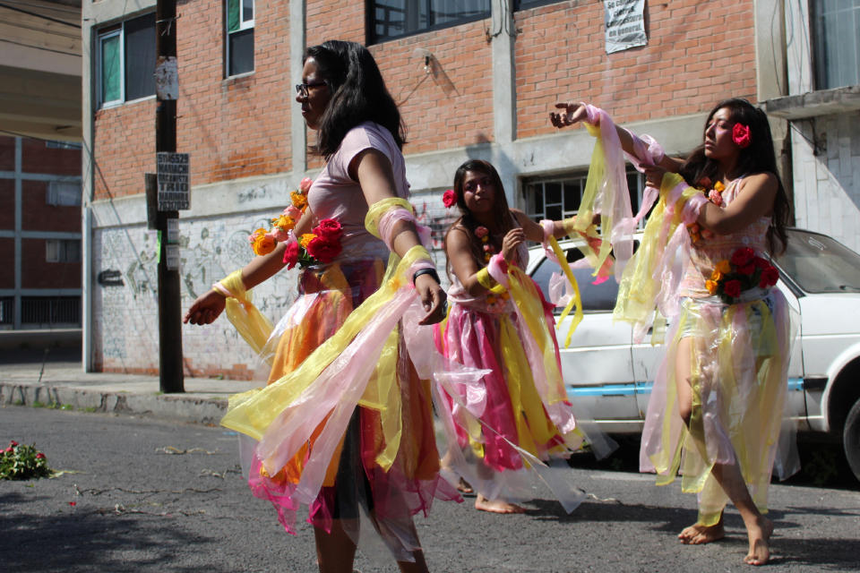 Women dance barefoot on asphalt, clothed in shreds of organza in pastel shades of pink and yellow, the favorite colors of murder victim Briseida Carreno, during a ceremony in her honor, in Ecatepec, a suburb of Mexico City, Saturday, Nov. 23, 2019. The flowers they are wearing stood for hope and healing, while the shredded fabric represented the tattered lives of victims and their families. (AP Photo/Amy Guthrie)