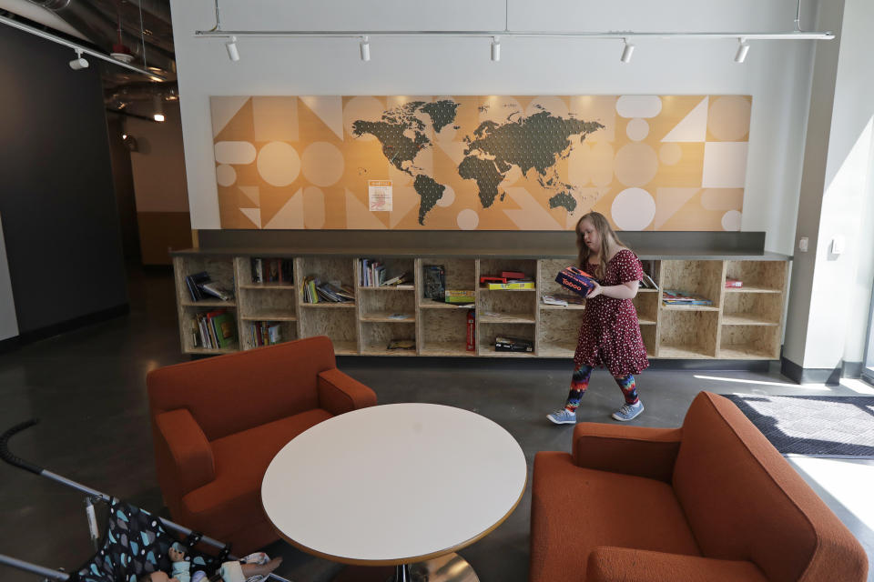 Emilyanne Wade, 12, carries a game as she walks in a common area Wednesday, June 17, 2020, at Mary's Place, a family homeless shelter located inside an Amazon corporate building on the tech giant's Seattle campus. The facility is home to the Popsicle Place shelter program, an initiative to address the needs of homeless children with life-threatening health conditions. (AP Photo/Ted S. Warren)