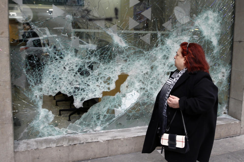 A woman looks at the broken glass of Bank of Beirut that was smashed by anti-government protesters in Beirut, Lebanon, Wednesday, Jan. 15, 2020. Banks in Hamra trade street were badly damaged after a night that witnessed clashes between anti-government protesters and Lebanese riot police. (AP Photo/Bilal Hussein)