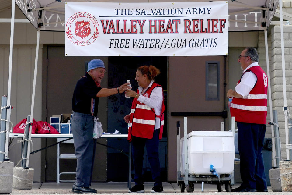 Salvation Army volunteer Francisca Corral, center, gives water to a man at a their Valley Heat Relief Station, Tuesday, July 11, 2023 in Phoenix. Even desert residents accustomed to scorching summers are feeling the grip of an extreme heat wave smacking the Southwest this week. Arizona, Nevada, New Mexico and Southern California are getting hit with 100-degree-plus Fahrenheit temps and excessive heat warnings. (AP Photo/Matt York)