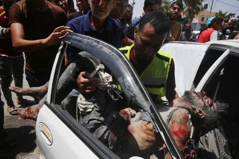 Palestinian men carry the body of a dead person at Al-Aqsa Martyrs Hospital following simultaneous Israeli attacks on Nuseirat Refugee Camp, al-Bureij Refugee Camp and al-Maghazi Refugee Camp. Israeli special forces rescued four hostages in broad daylight on Saturday from the Nuseirat refugee district in the centre of the Gaza Strip after 246 days in captivity, the army said. Omar Naaman/dpa