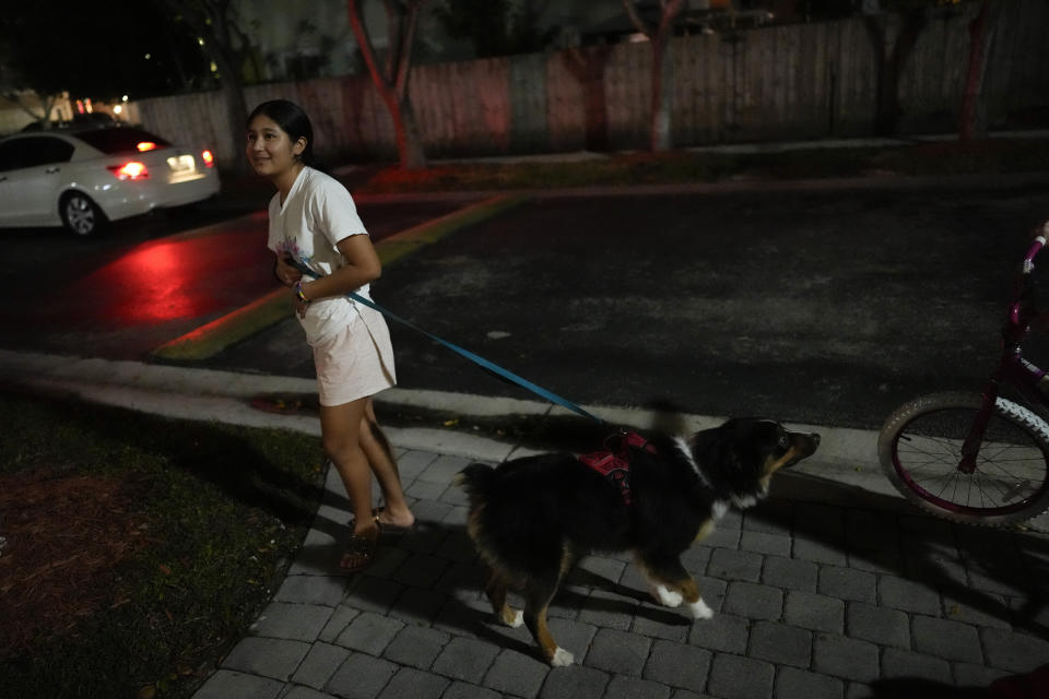 Sol, a 14-year-old from Argentina, walks her dog, Cosmo, which her foster parents gave her for earning all A's even though she crossed the border knowing very little English, in Homestead, Fla., Monday, Dec. 18, 2023. Sol is among tens of thousands of children who have arrived in the United States without a parent during a huge surge in immigrants that's prompting congressional debate to change asylum laws. (AP Photo/Rebecca Blackwell)
