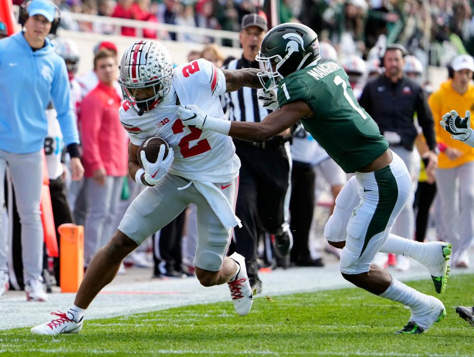 Oct 8, 2022; East Lansing, Michigan, USA; Ohio State Buckeyes wide receiver Emeka Egbuka (2) gets tackled by Michigan State Spartans safety Jaden Mangham (1) after a catch in the first quarter of the NCAA Division I football game between the Ohio State Buckeyes and Michigan State Spartans at Spartan Stadium. 
