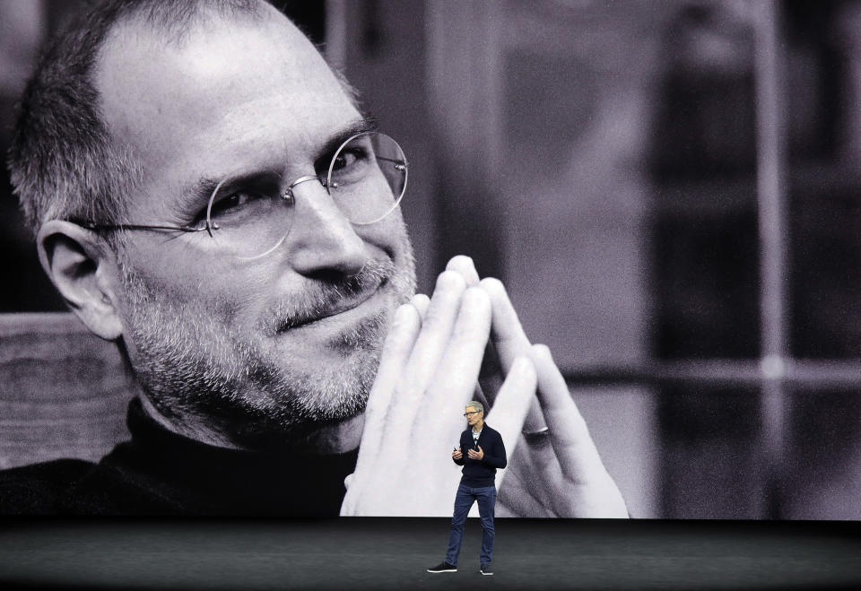 With a photo of former Apple co-founder and CEO Steve Jobs projected in the background, Apple CEO Tim Cook kicks off the event for a new product announcement at the Steve Jobs Theater on the new Apple campus, Tuesday, Sept. 12, 2017, in Cupertino, Calif. (AP Photo/Marcio Jose Sanchez)