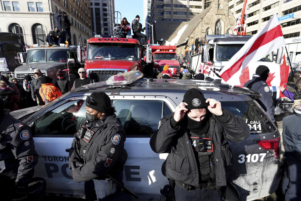 Trucks attempting to drive down University Avenue between Bloor Street and Queen's Park are blocked by a police cruiser during a demonstration in support of a trucker convoy in Ottawa protesting COVID-19 restrictions, in Toronto, Saturday, Feb. 5, 2022. (Nathan Denette/The Canadian Press via AP)