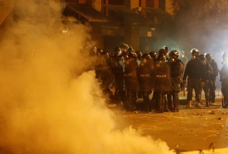 Smoke rises as riot police stand together during a protest against a ruling elite accused of steering Lebanon towards economic crisis in Beirut