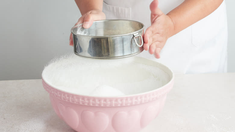 woman sifting sugar into bowl