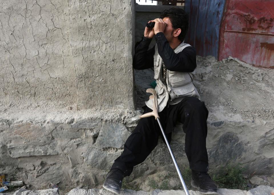 An Afghan man uses a pair of binoculars near the site of an attack in Kabul
