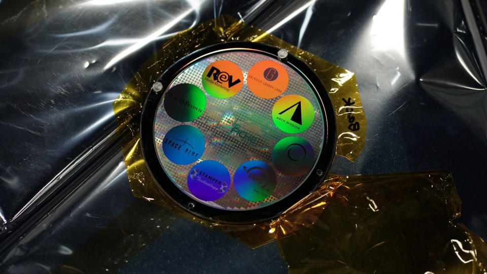 closeup of a small silver disk with colorful stickers stuck around its face in a circle.