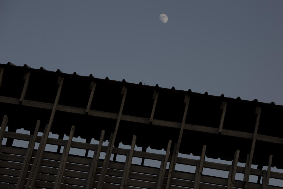 The moon rises over the Mughrabi Bridge, a wooden pedestrian bridge connecting the wall to the Al Aqsa Mosque compound, in Jerusalem's Old City, Tuesday, July 20, 2021. The rickety bridge allowing access to Jerusalem's most sensitive holy site is at risk of collapse, according to experts. But the flashpoint shrine's delicate position at ground-zero of the Israeli-Palestinian conflict has prevented its repair for more than a decade. (AP Photo/Maya Alleruzzo)