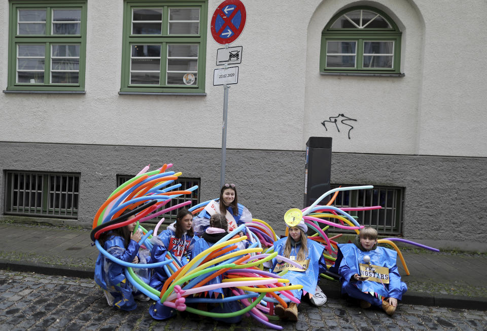 Carnival performers sit at the roadside after a carnival parade was cancelled in due to severe weather conditions in Cologne, Germany, Sunday, Feb. 23, 2020. (Oliver Berg/dpa via AP)