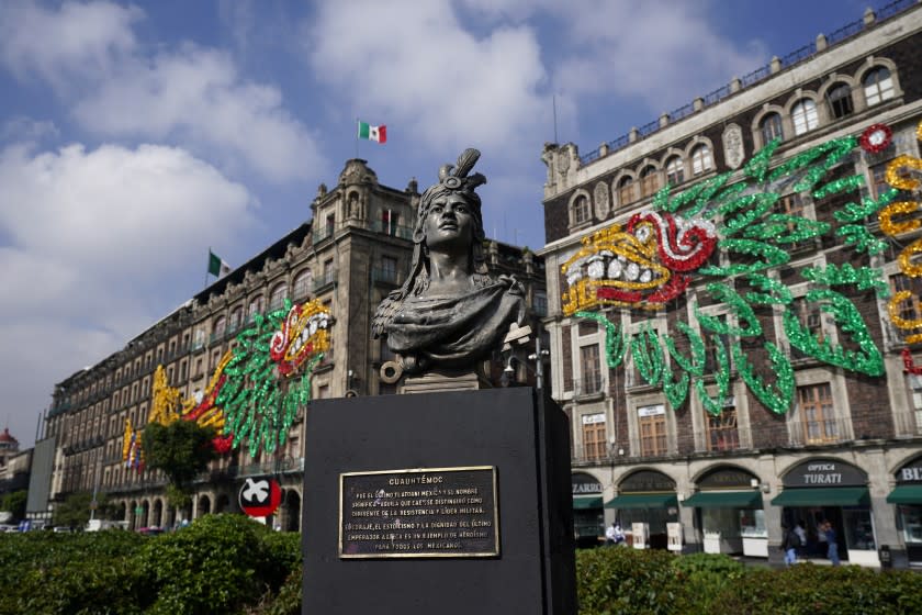A bust of Aztec emperor Cuauhtemoc is backdropped by an image of the Pre-columbian god Quetzalcoatl adorning the surrounding buildings, at Mexico City´s main square the Zocalo, Monday, Aug. 9, 2021. Mexico City is preparing for the 500 anniversary of the fall of the Aztec capital of Tenochtitlan, today´s Mexico City, on Aug. 13, 2021. (AP Photo/Eduardo Verdugo)