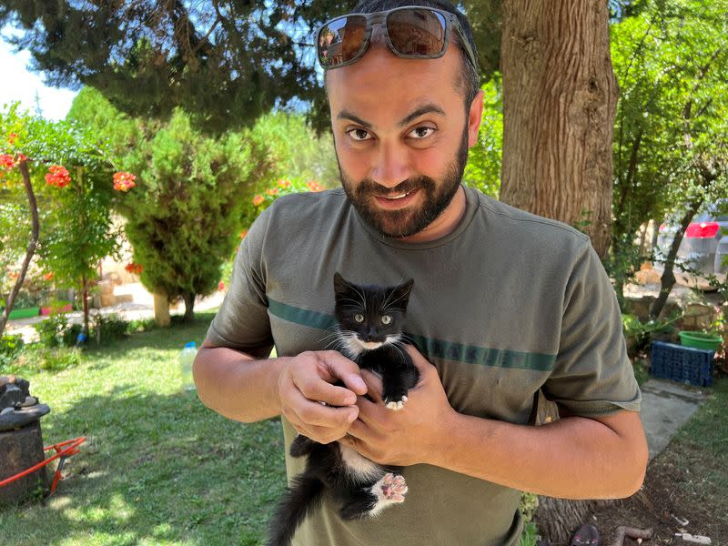 Reuters visuals journalist Issam Abdallah holds a kitten while posing for a picture in Saaideh, Lebanon