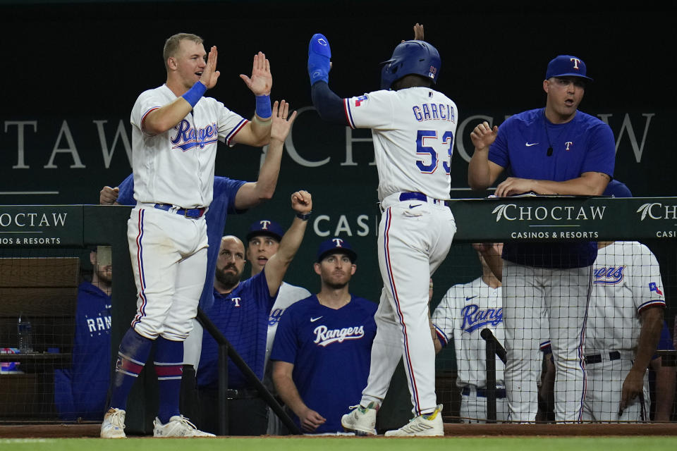 Texas Rangers' Adolis Garcia (53) is greeted near the dugout by Josh Jung, left, after scoring a double by Jonah Heim during the sixth inning of a baseball game against the Boston Red Sox, Tuesday, Sept. 19, 2023, in Arlington, Texas. (AP Photo/Julio Cortez)