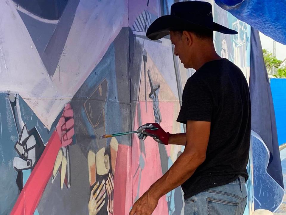 Artist Roberto Marquez paints on a mural at the memorial wall on Harding Avenue in Surfside, Florida, Saturday, July 10, 2021.