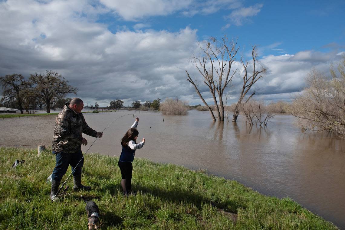 Tim Williamson and his daughter Violet, 6, do some fishing in the flooded parking lot at the San Joaquin Fishing Access on the San Joaquin River in Patterson, Calif., Wednesday, March 22, 2023.