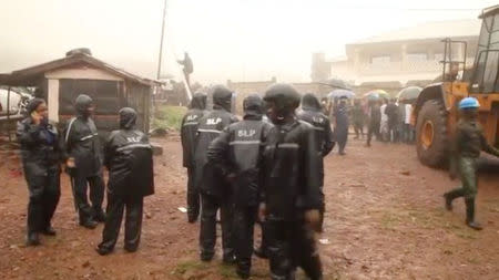 Police officers stand at the site after a mudslide in the mountain town of Regent, Sierra Leone August 14, 2017 in this still image taken from a video. REUTERS/Reuters TV