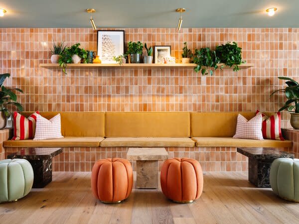 The lobby bench wall features Waterworks tile in Spice, Glossy Crackle and artwork from House of Spoils, on the shelf. The poufs and side tables are from Soho Home.