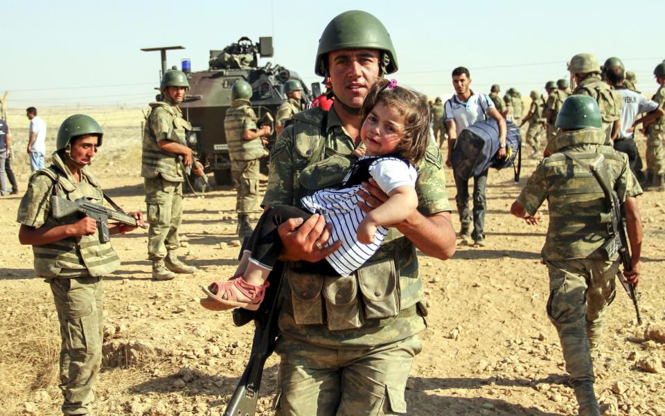 A Turkish soldier carries a Syrian girl as she enters&nbsp;Turkey at the Akcakale border crossing on June 6. Over <a href="http://www.huffingtonpost.com/entry/how-to-help-refugees-winter_5630d376e4b00aa54a4bfc17">4 million Syrians</a> have sought refuge in neighboring countries to flee airstrikes and fighting in the country.