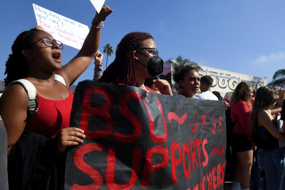 Jayden Johnson, left, Gwen Withers, Jazmin Kinchlow and Leia Ludy of Ventura High's Black Student Union hold up a sign as they join hundreds of other students in a walkout Friday to support more pay for teachers and staff.