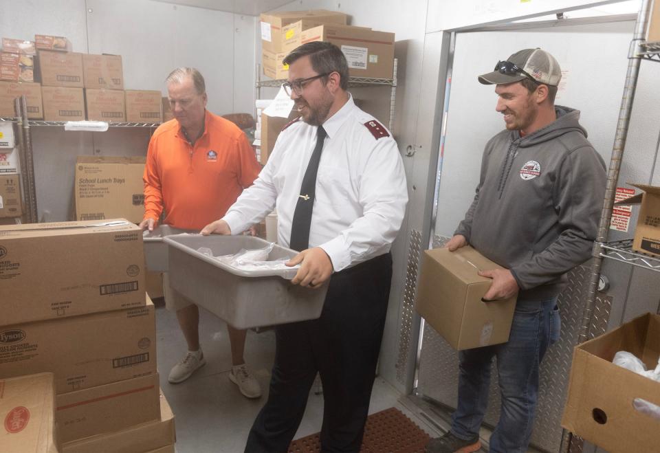 Brennen Hinzman, center, captain and pastor at the Salvation Army of Massillon, helps unload boxes of donated pork last week given to the organization by Stark County Commissioner Richard Regula, left, and Navarre farmer Jack Flinner.