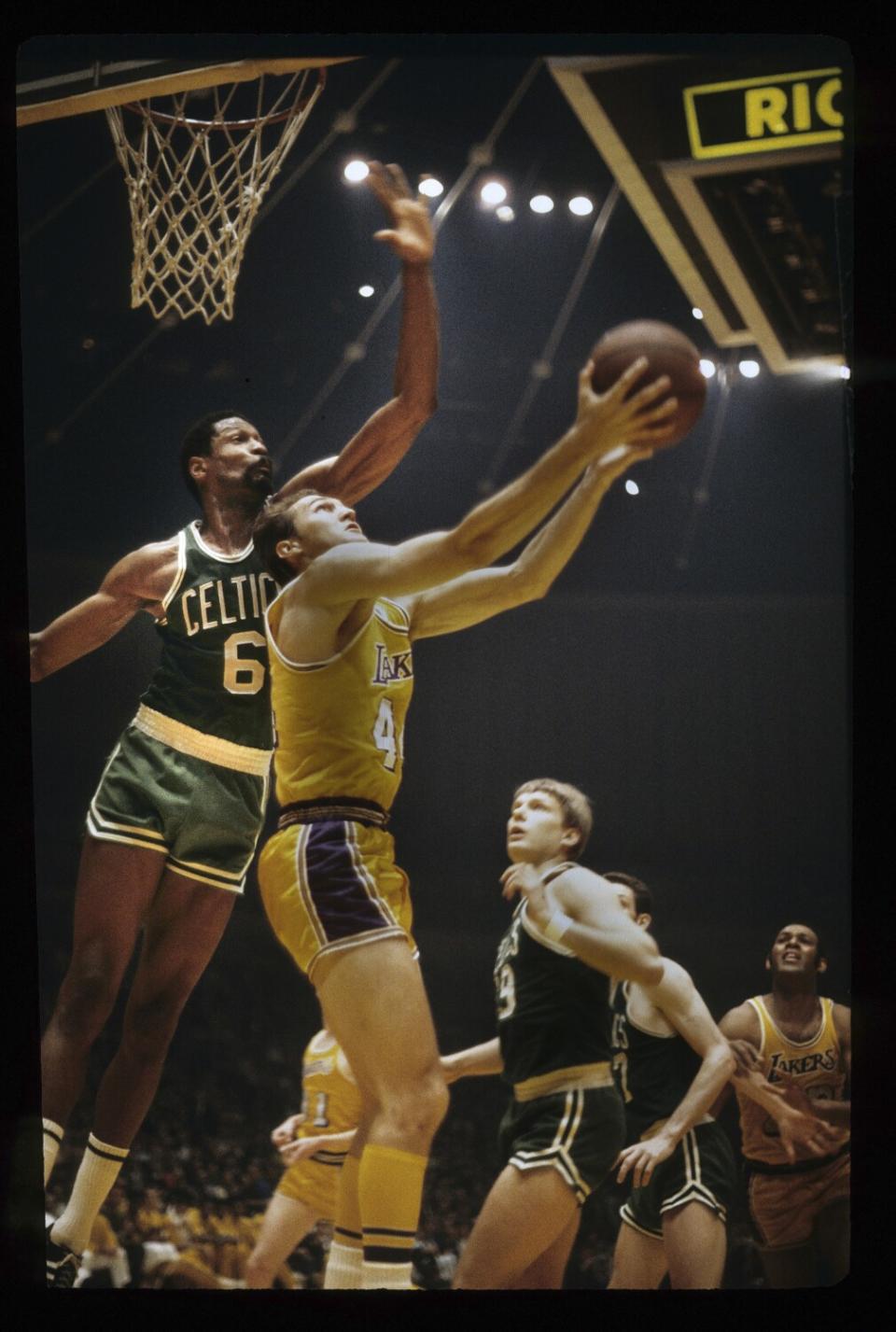 Celtics center Bill Russell tries to block a layup by Lakers guard Jerry West.