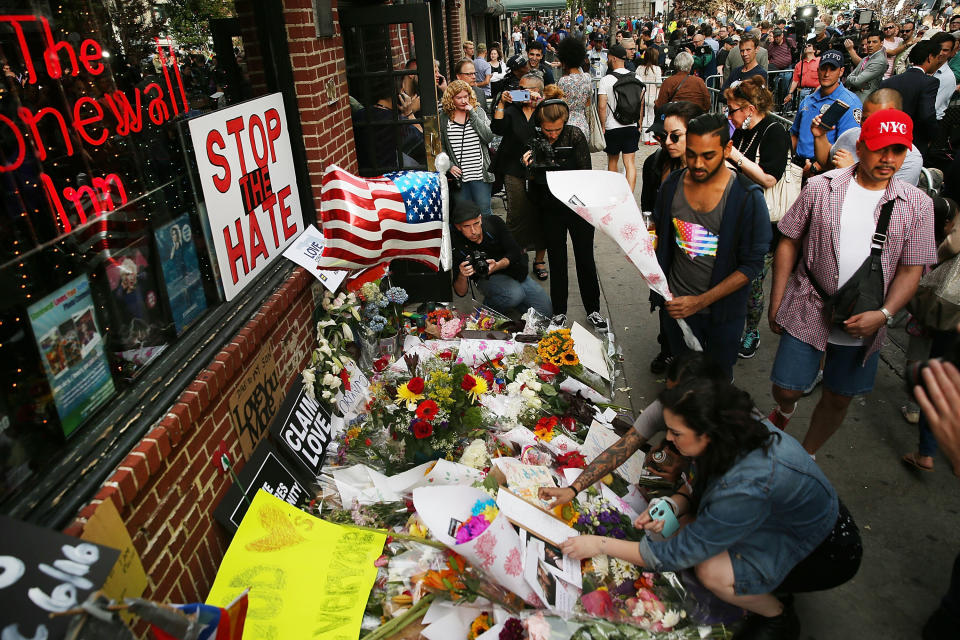 People pause in front of the iconic New York City gay and lesbian bar The Stonewall Inn to lay flowers and grieve for those killed in Orlando on June 13, 2016 in New York City.&nbsp;