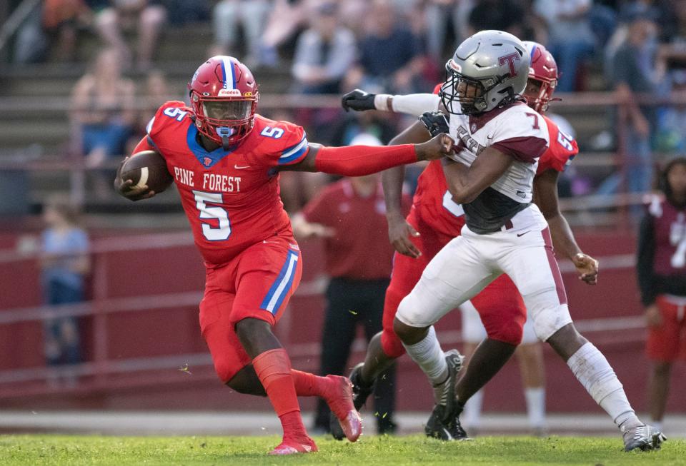 Quarterback T.J. Wilson (5) evades the pressure of Marcel Davis (7) during the Tate vs Pine Forest football game at Pine Forest High School in Pensacola on Thursday, Aug. 25, 2022.