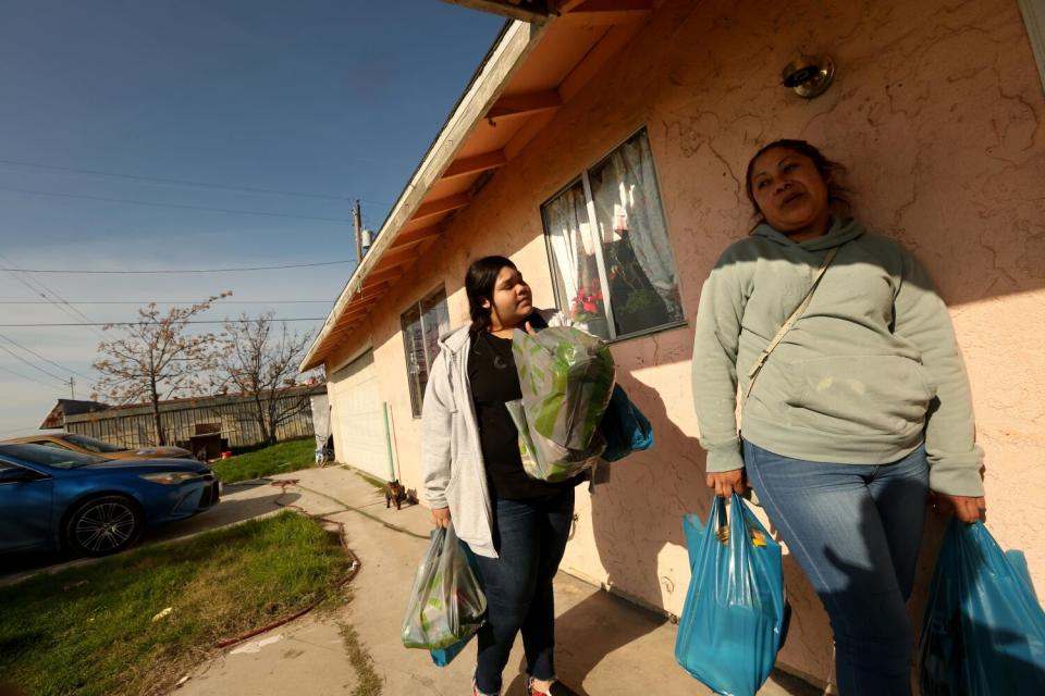 A mother and daughter carry groceries home.