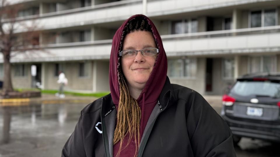 Melissa Maheu, a resident of the Overbrook apartment building, is photographed on May 8, 2024. She is standing in front of her building that caught fire on May 2.