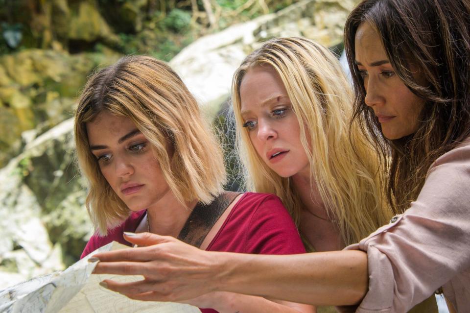 Three women look at a map in the middle of the jungle