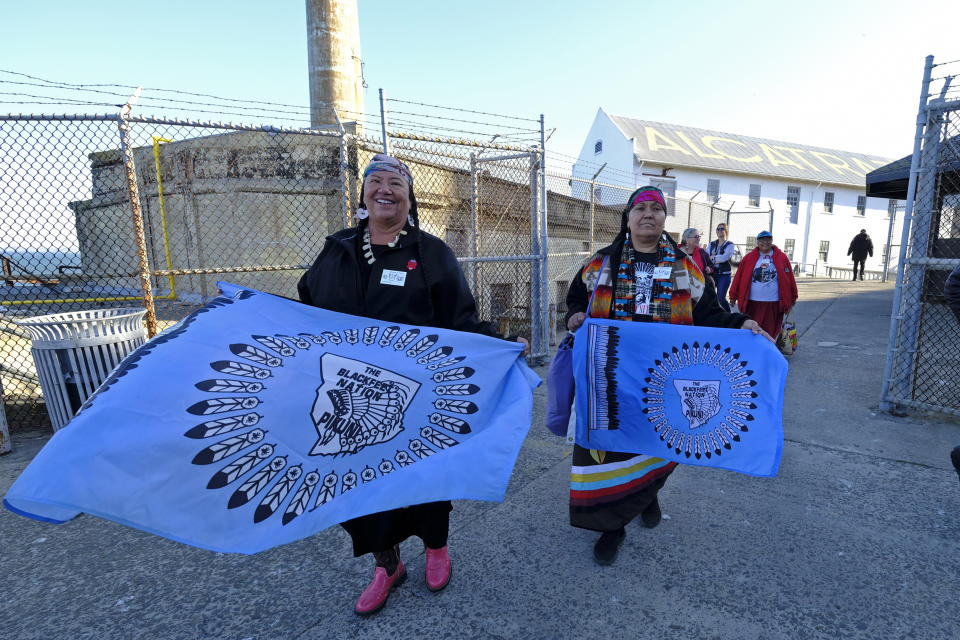 Theda New Breast, left, and Aurora Mamea, of the Blackfeet Nation in Montana, make their way to ceremonies for the 50th anniversary of the Native American occupation of Alcatraz Island Wednesday, Nov. 20, 2019, in San Francisco. About 150 people gathered at Alcatraz to mark the 50th anniversary of a takeover of the island by Native American activists. Original occupiers, friends, family and others assembled Wednesday morning for a program that included prayer, songs and speakers. They then headed to the dock to begin restoring messages painted by occupiers on a former barracks building. (AP Photo/Eric Risberg)