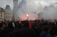 Protesters light up flares at the Old Town Square in Prague, Czech Republic, Sunday, Oct. 18, 2020. Czech police used tear gas and a water cannon to disperse crowd of hundreds of violent protesters who attacked them after a rally in Prague against the government's restrictive measures imposed to slow the spread of the coronavirus infections. (AP Photo/Petr David Josek)