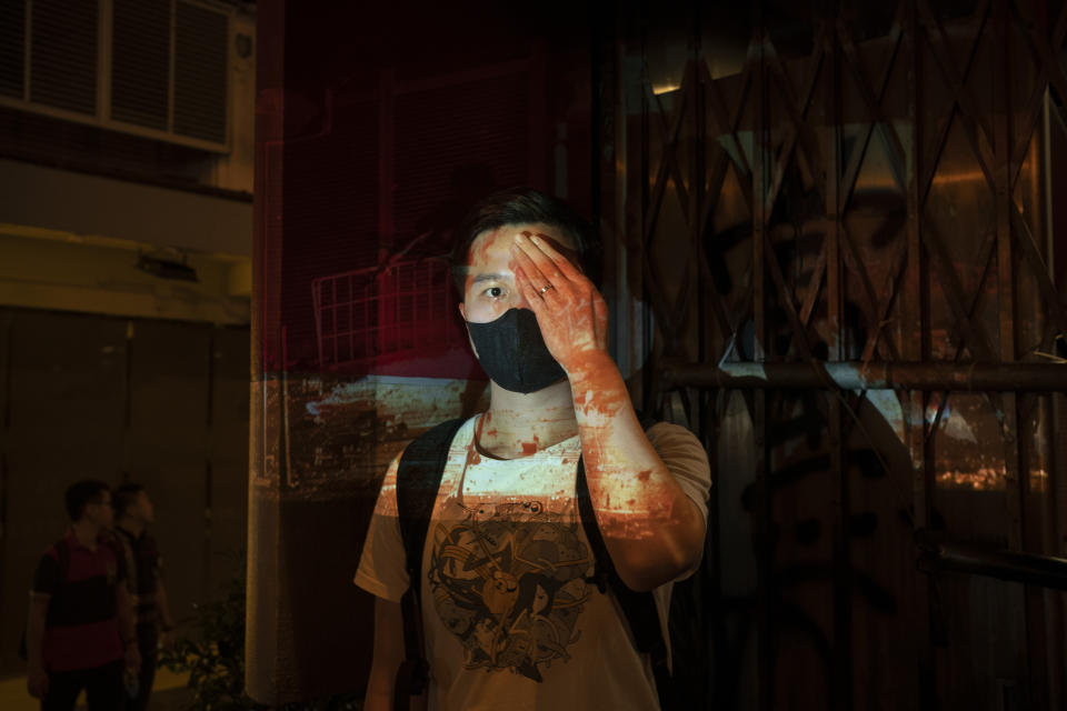 A protester who identified himself as Tom, poses for a portrait next to a damaged subway station as a projector displays a photograph, previously taken during the unrest, over him at a protest in Hong Kong. Tom said "If we don't wear the mask, the police can recognize you and say you are a rioter and arrest you for no reason, even if you are peacefully protesting. That's the white terror they want to do."  (Photo: Felipe Dana/AP)