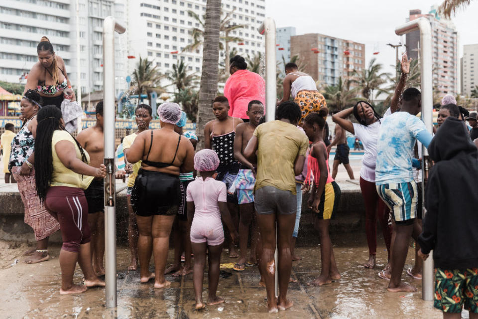 Beachgoers rinse themselves under a shower along Durban&#39;s Golden Mile beach front in Durban.