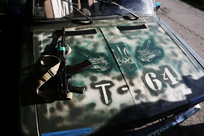 A weapon of Ukrainian serviceman is seen on a car bonnet painted with tanks in Kharkiv