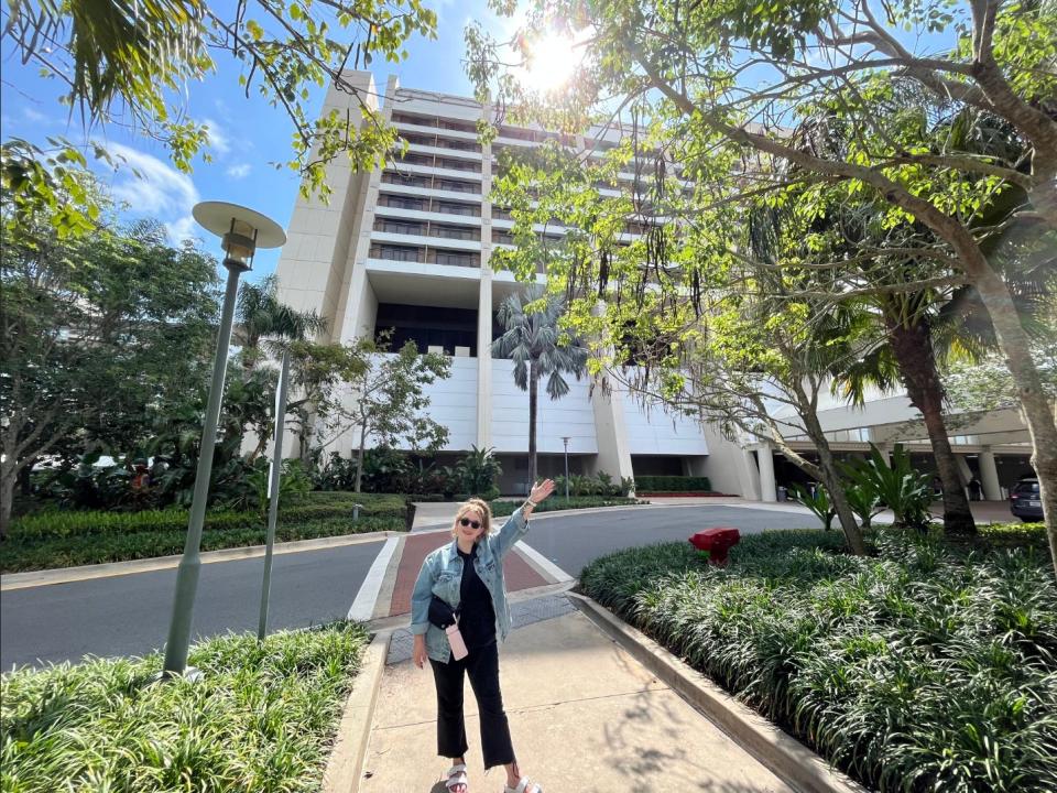 Jacqueline poses with her arm in the air outside a Disney hotel.